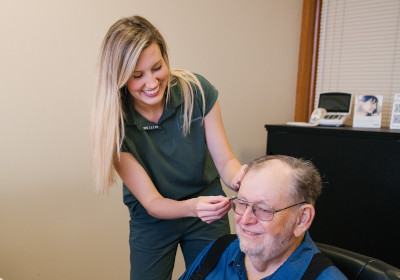 Dr. Lenhard fitting a smiling patient with hearing aids